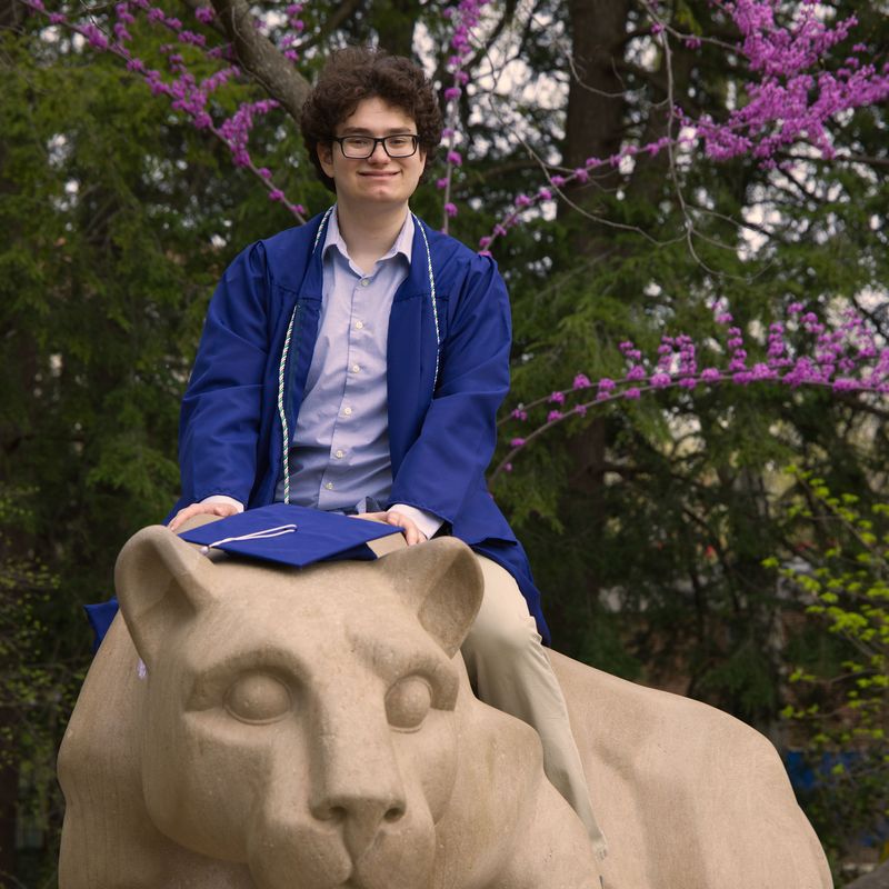Graduate sitting on the Nittany Lion Shrine