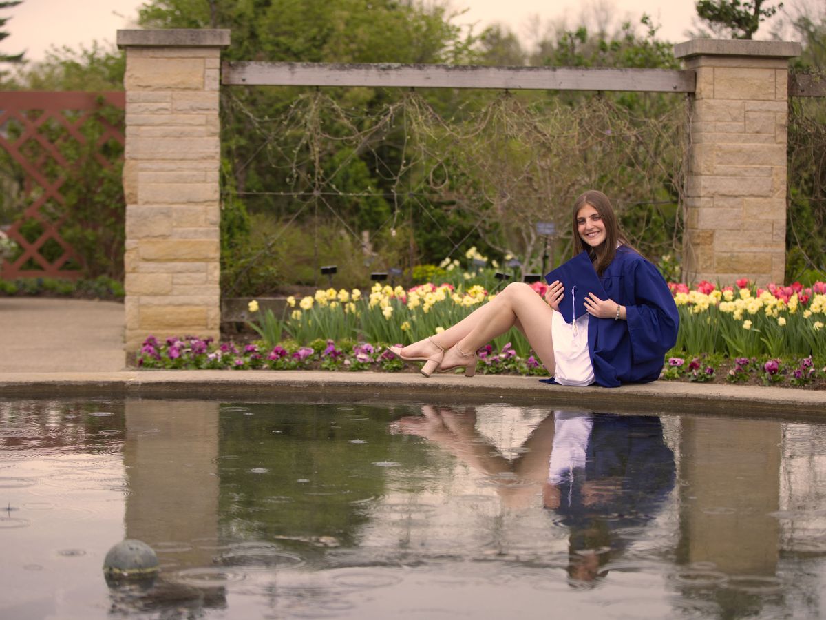 Graduate by the reflecting pool and tulips in the Arboretum